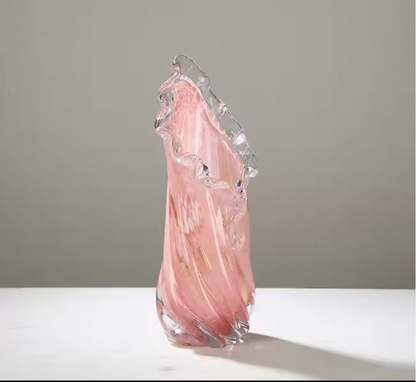 Pink glass sculpture on a white surface with a gray background