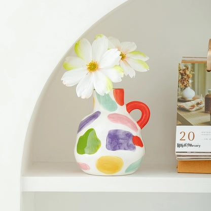 Colorful vase with a white flower on a shelf