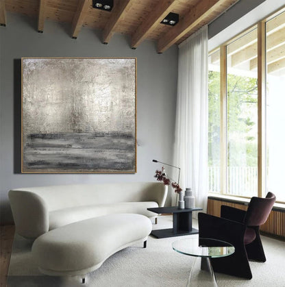 Modern living room with a white sofa, abstract painting, and large windows.