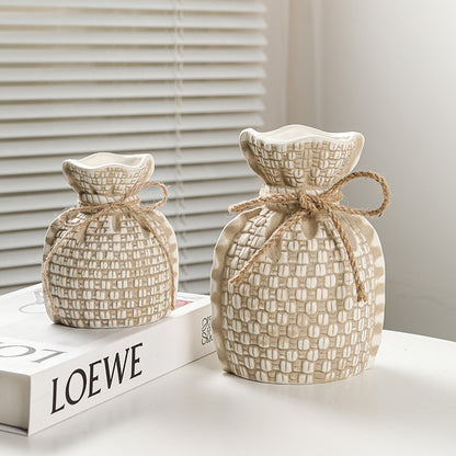 Two woven fabric bags tied with jute rope on a LOEWE box with a neutral background.