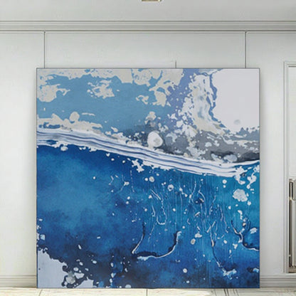 Abstract art piece with blue, white, and gray colors on a white wall.