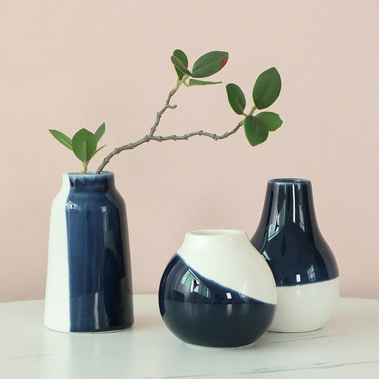 Three ceramic vases with blue and white gradient on a light surface with a beige background.