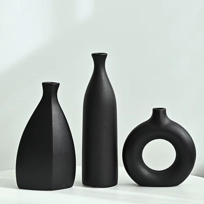 Three black vases of different shapes on a light gray background