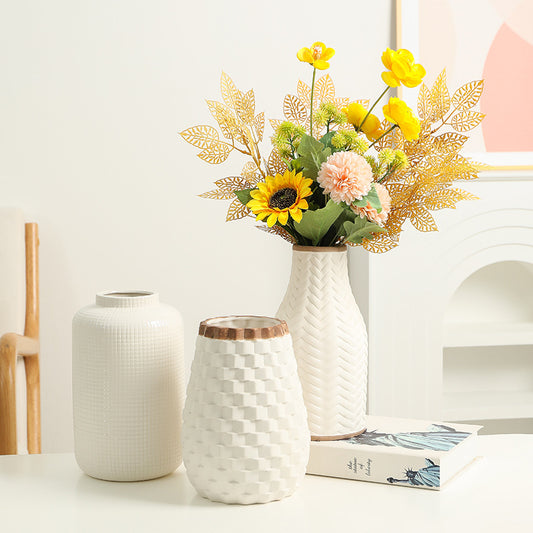 Three white textured vases with a floral arrangement on a light surface.