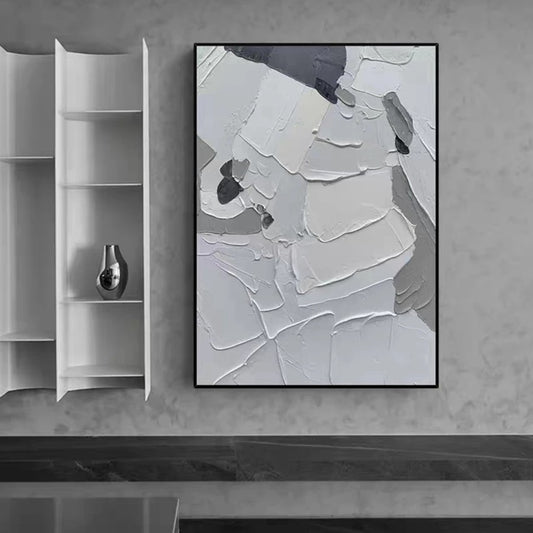 Abstract art piece on a gray wall with a white shelf and vase.