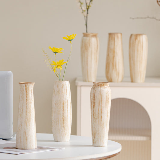 Set of wooden vases with yellow flowers on a table against a neutral background
