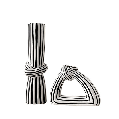 Black and white striped ceramic vase and triangle-shaped ornament on a white background