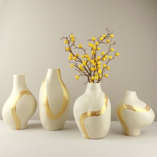 Set of four decorative vases with gold accents on a plain background