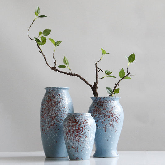 Three blue ceramic vases with speckled pattern on a white surface and light gray background.