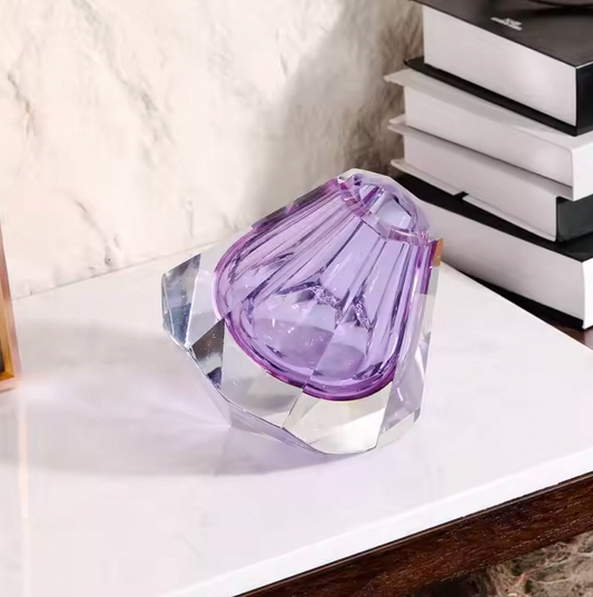 Purple and clear crystal object on a white surface with books in the background