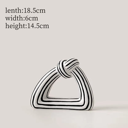 Black and white striped geometric sculpture on a light gray background