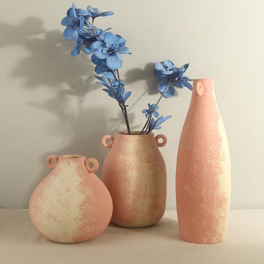 Three terracotta vases of different shapes and sizes with blue flowers on a neutral background