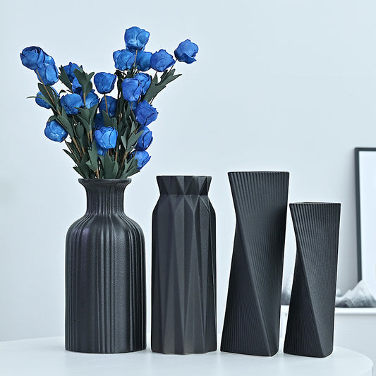 Set of four black vases with geometric designs on a light blue background