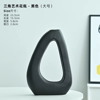 Black artistic vase on a white surface with product details in the background