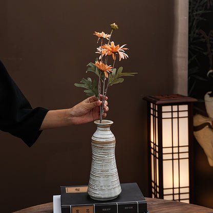 Person arranging flowers in a textured vase with a warm light lamp in the background