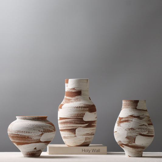 Three ceramic vases with brown and white patterns on a gray background