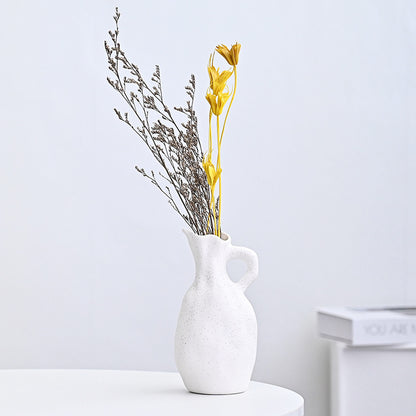 White ceramic vase with dried flowers on a light gray background