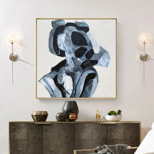 Abstract art piece in a gold frame above a console table with decorative items.