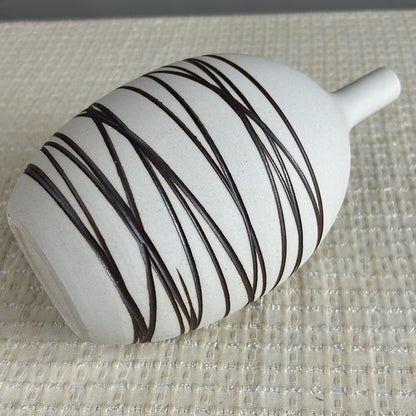 White vase with black stripes on a textured surface
