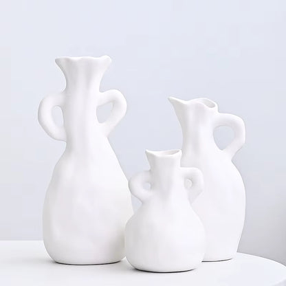 Three white ceramic vases of different shapes on a light gray background