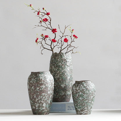 Three textured vases with a branch of red flowers on a light gray background