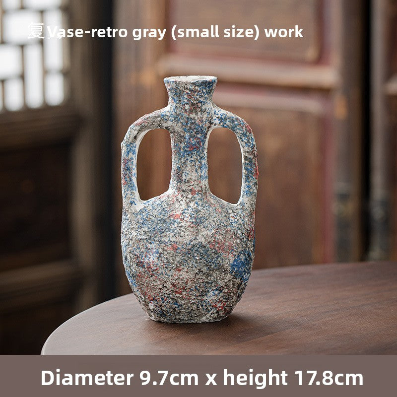 Retro gray ceramic vase with two handles on a wooden surface, blurred background