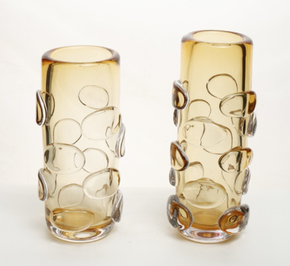 Two amber glass vases with decorative patterns on a white background