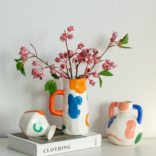 Colorful ceramic vases with abstract designs on a white surface.
