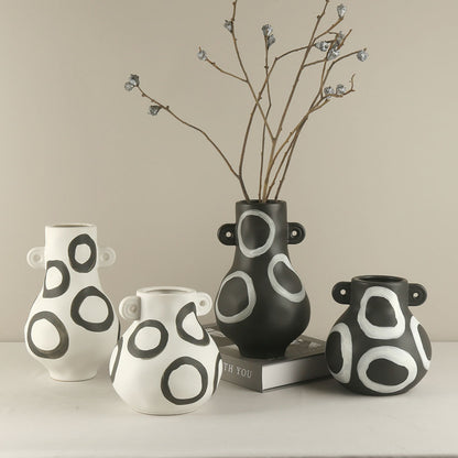 Set of four black and white patterned vases on a neutral background