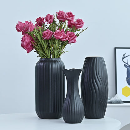 Three dark gray vases with a bouquet of pink roses on a light blue background
