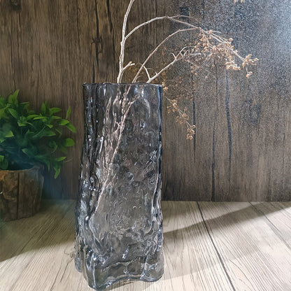 Decorative glass vase with textured surface on a wooden floor against a wooden wall.