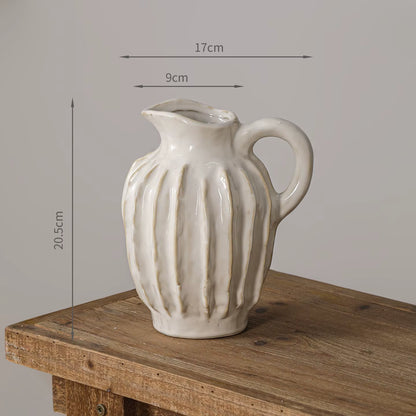White ceramic pitcher with ribbed texture on a wooden surface, measurements indicated.