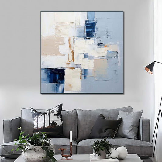 Abstract art painting on a wall above a gray sofa in a living room.