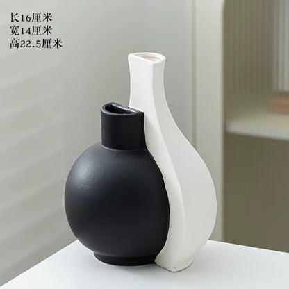 Two ceramic vases, one black and one white, on a light surface with a neutral background.