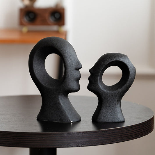 Two black abstract sculpture figures on a wooden surface