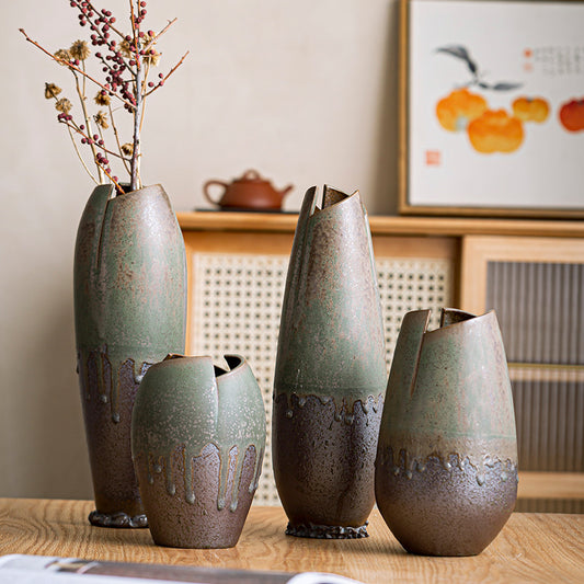 Set of three ceramic vases on a wooden surface with a framed artwork in the background.