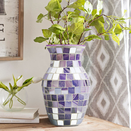 Mosaic-patterned vase with green branches on a wooden surface
