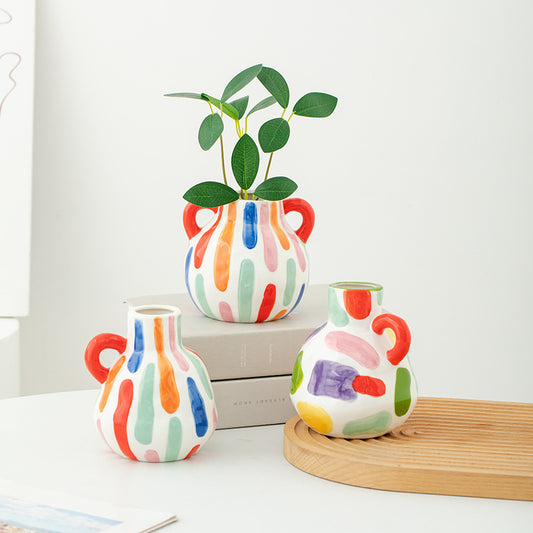 Colorful ceramic vases with abstract patterns on a white surface.