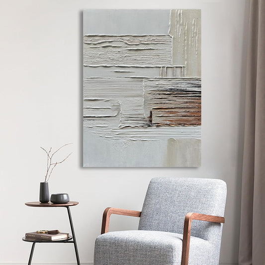 Abstract painting on a wall above a gray armchair in a room.