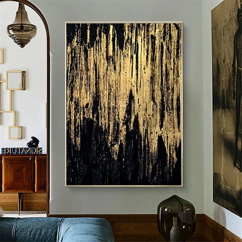 Abstract art piece with gold and black colors on a wall in a room.