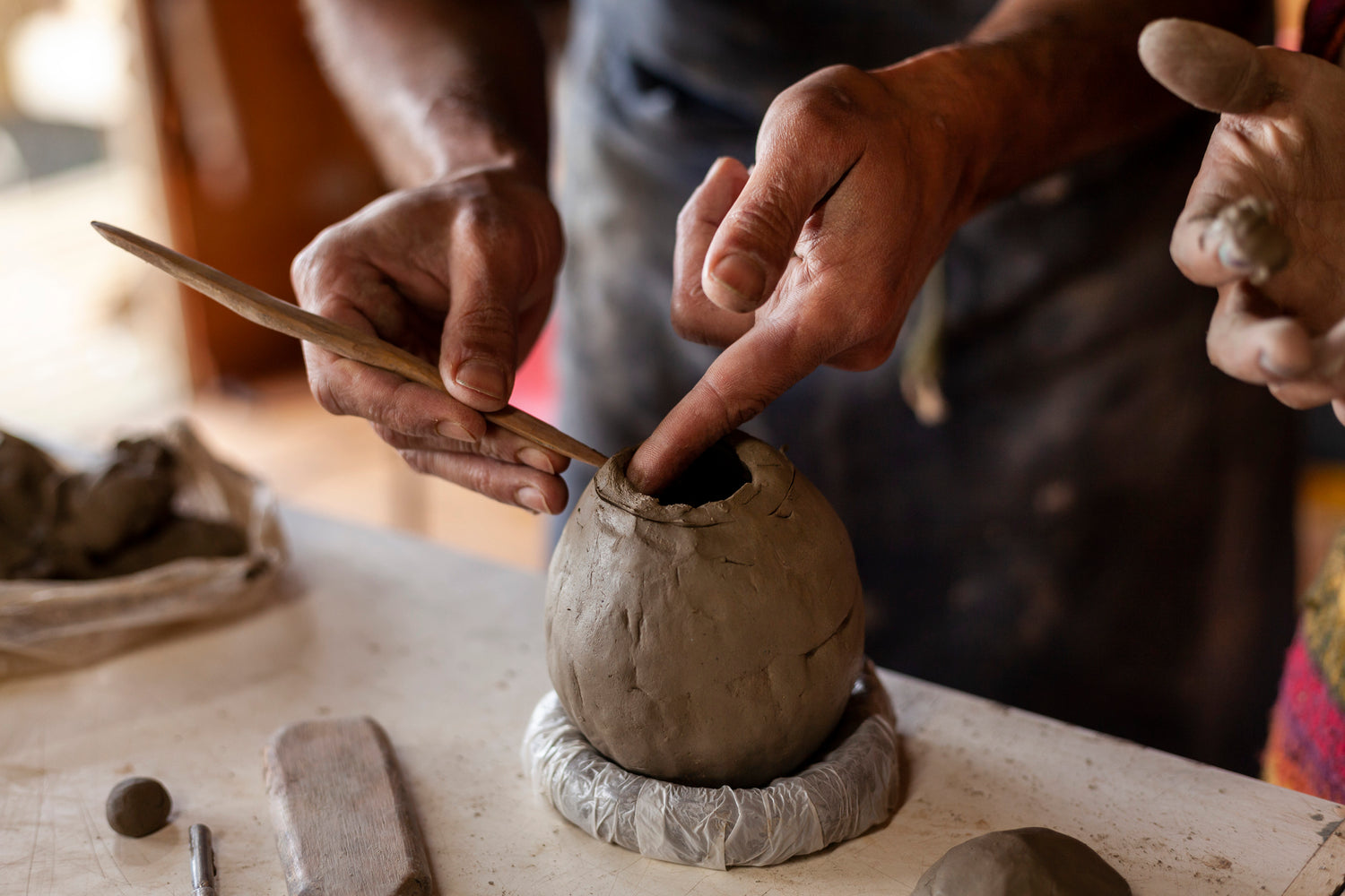 Person working with clay on a pottery wheel in a workshop setting