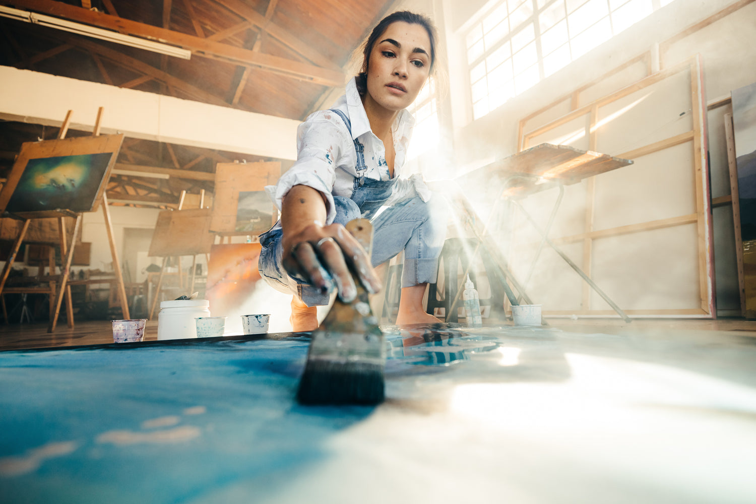 Person painting on a large canvas in an art studio