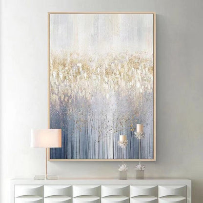 Abstract painting with gold and blue tones on a gray wall above a white console table.