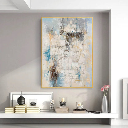 Abstract painting in a gold frame on a wall above a shelf with decorative items.
