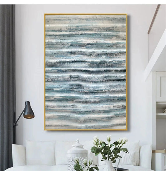 Abstract painting in a gold frame on a wall above a white sofa in a living room.